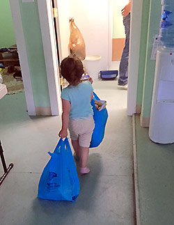 small child helping to carry supplies