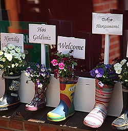 boots at a doorway stuffed with welcome signs